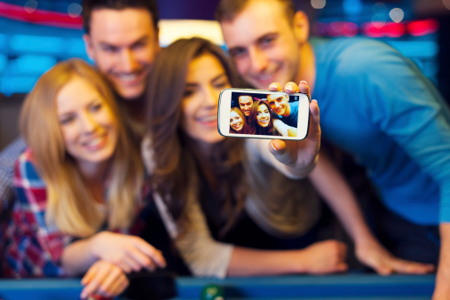 Smiling friends taking selfie photo from nightclub with billiard