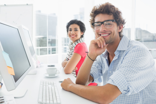Smiling casual couple at desk in office