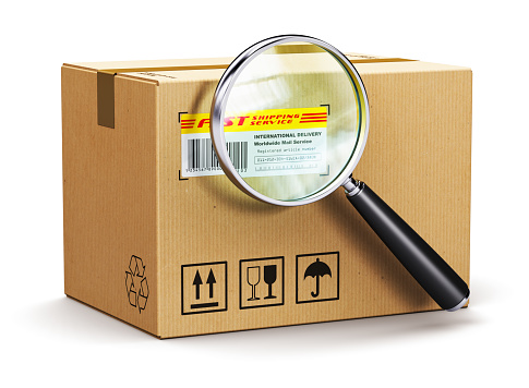 Cardboard box parcel with tracking number and magnifying glass