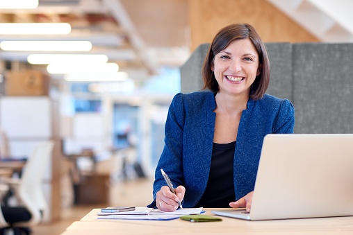 Busineswoman smiling broadly while working in her office cubicle